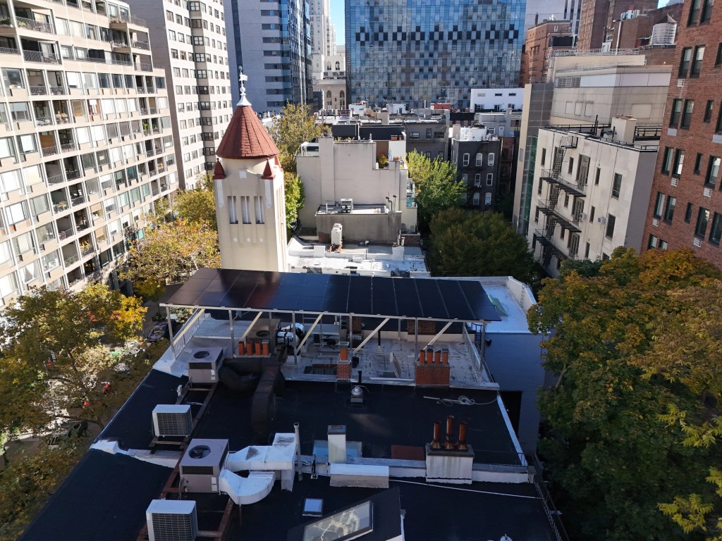 Solar panels installed on a rooftop in a dense urban city with surrounding residential and commercial buildings