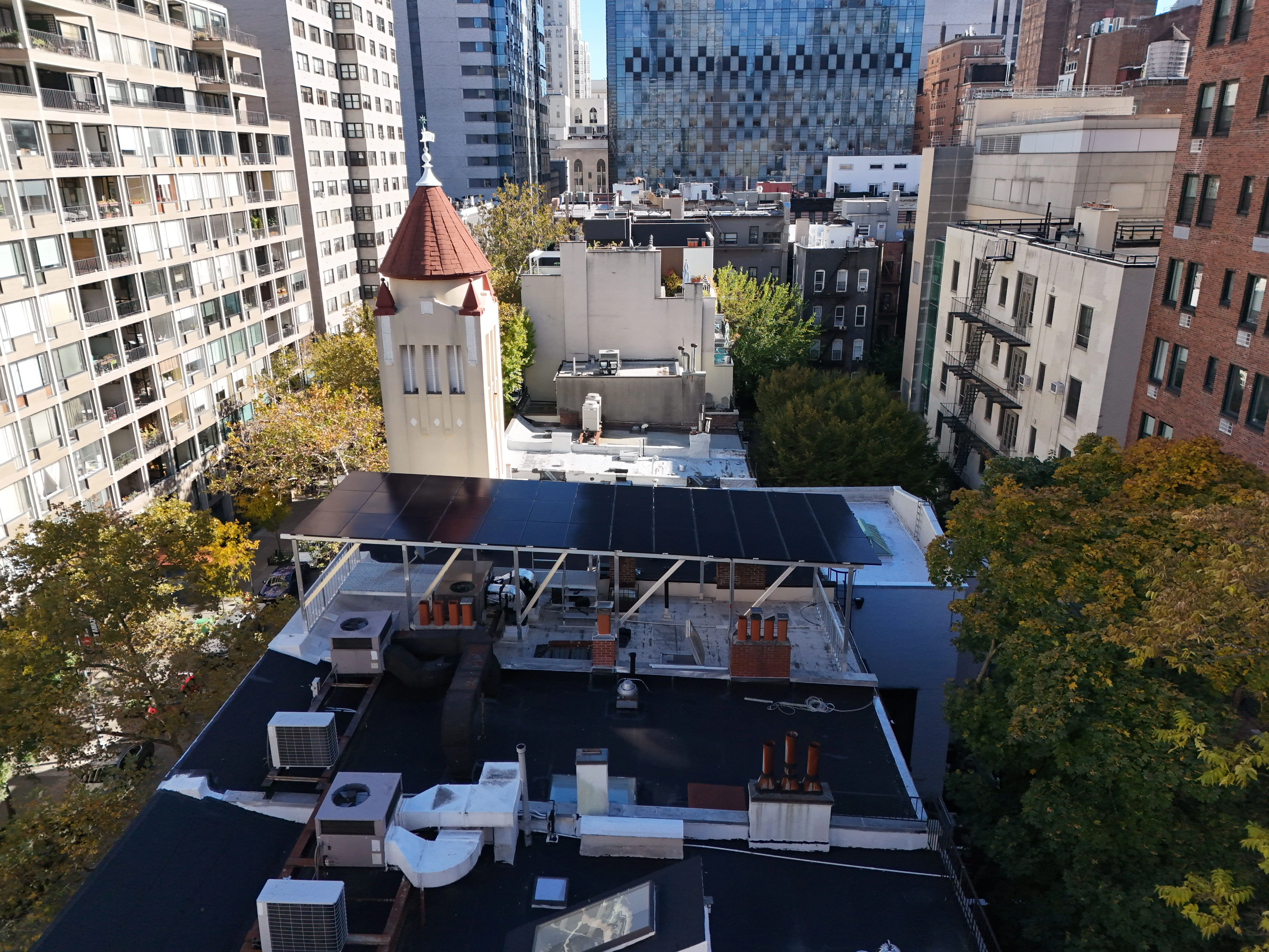 Solar panels installed on a rooftop in a dense urban city with surrounding residential and commercial buildings