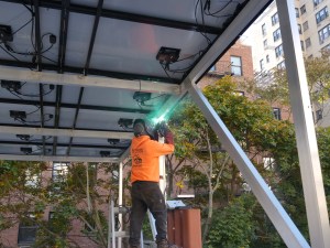 Worker welding metal frame for rooftop solar panel installation on residential building